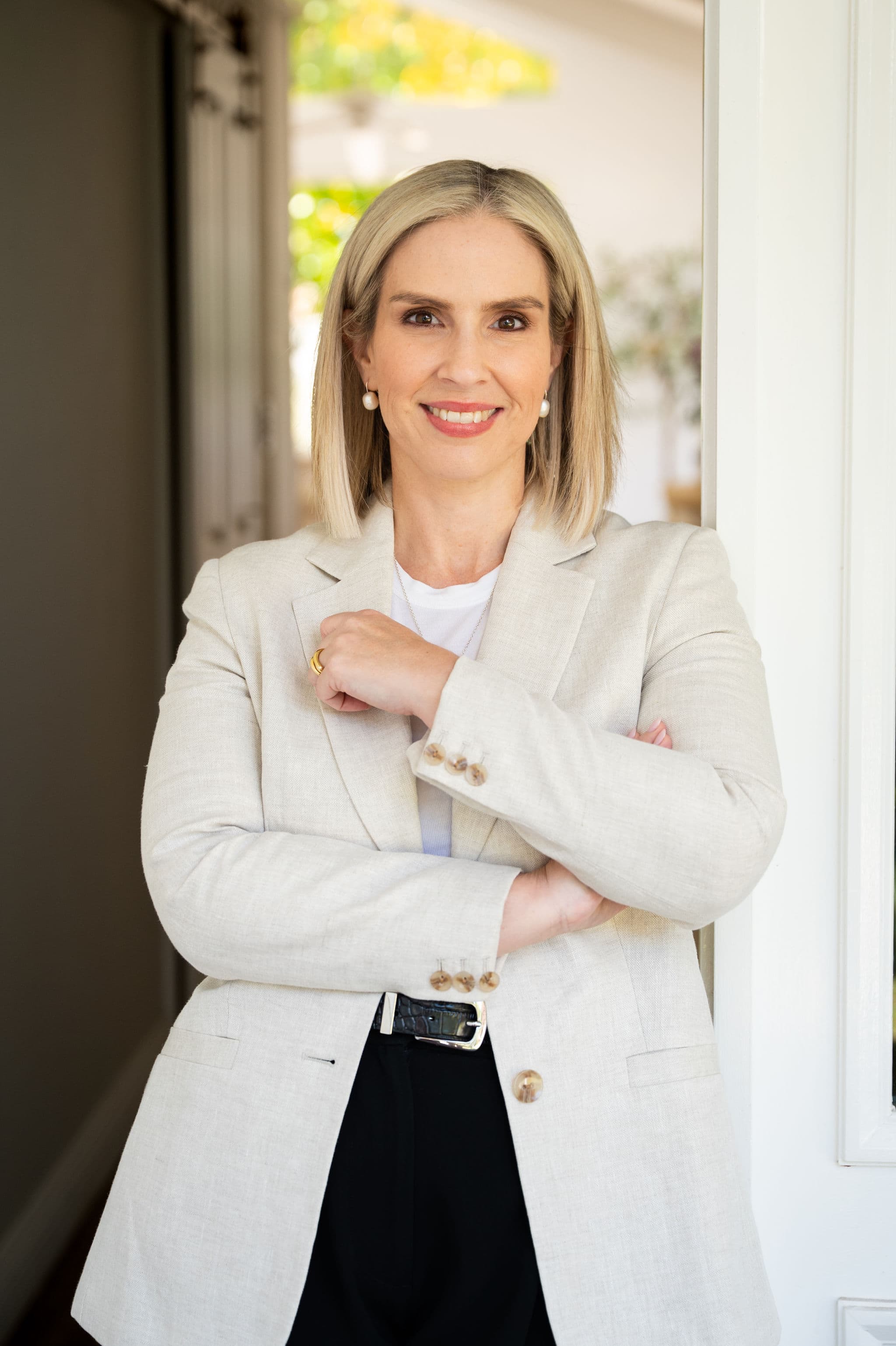 Confident portrait of Alana Salsano, Director at West End Settlements, in a linen blazer with arms crossed, leaning in a bright doorway.